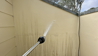 technicians in protective suits performing high-pressure washing on a building exterior in Sydney — Professional Cleaners in Sydney